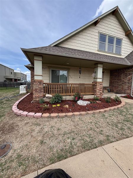 Curved flower bed with stone block border, orange mulch, and new flowers